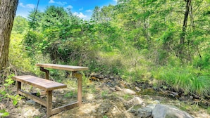 Ein Holztisch für ein Picknick in einem bewaldeten Gebiet mit einem Bach in der Nähe.