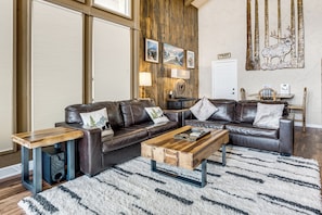 A living room with a brown leather sofa, a wooden coffee table, and a white shag rug. - Hot Tub Relaxation: Luxe Summit Gem w/ Mtn Views (Dillon)