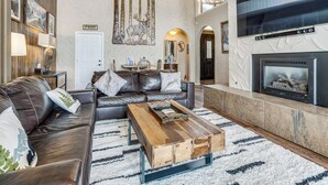A spacious living room with a leather sofa, a wooden coffee table, and a fireplace. - Hot Tub Relaxation: Luxe Summit Gem w/ Mtn Views (Dillon)