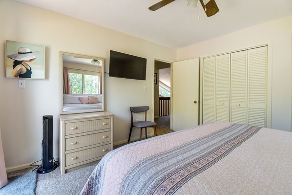 A bedroom with a bed, dresser, TV, and a closet.