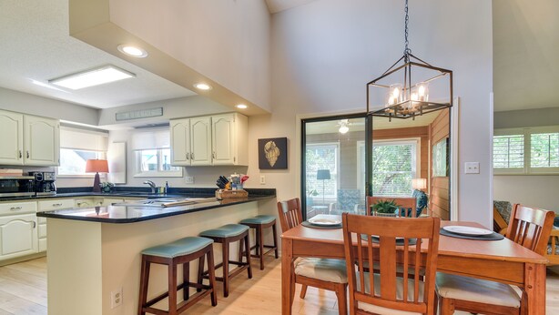 Una cocina amplia con una isla central, sillas de madera y una mesa de comedor.