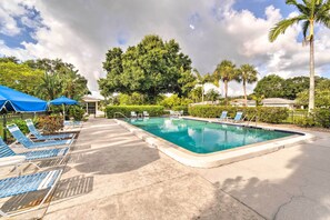 A swimming pool with lounge chairs and umbrellas, surrounded by trees and a gazebo. - Sunny Sarasota Oasis w/ Private Screened Lanai (Sarasota)