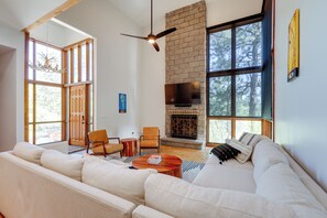 A spacious living room with a large sofa, a fireplace, and a television mounted on the wall. - Spacious Flagstaff Home w/ Hot Tub & Fire Pit! (Flagstaff)