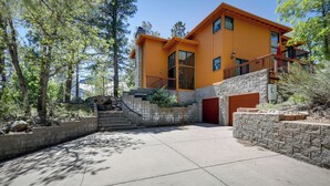 Una casa moderna de dos pisos con fachada de piedra y terraza de madera.
