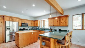 Una cocina amplia con armarios de madera, electrodomésticos de acero inoxidable y una isla grande con taburetes de bar.