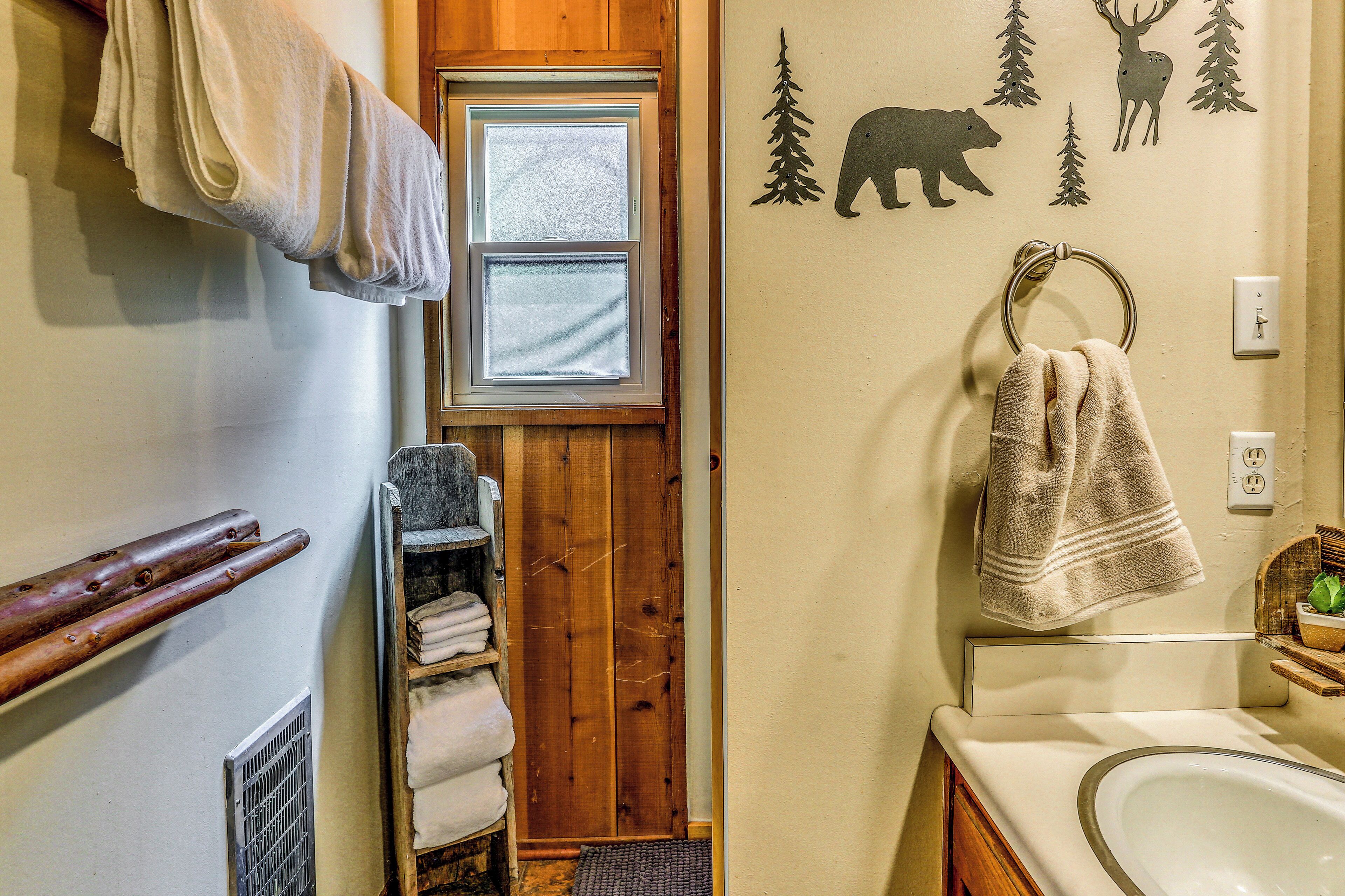 A bathroom with a wooden door, a window, a sink, and a towel rack.