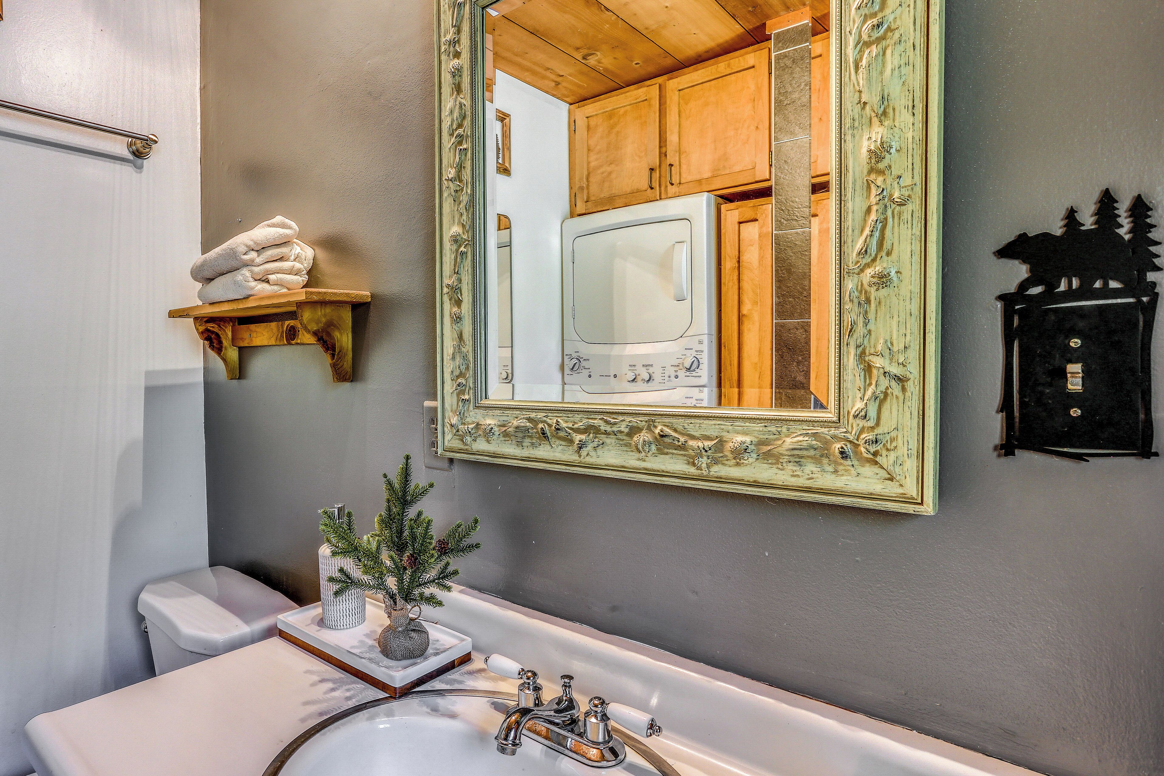 Une salle de bain avec des toilettes blanches, un lavabo doté d’un plan-vasque en marbre, un grand miroir avec un cadre orné et un porte-serviettes avec des serviettes pliées.