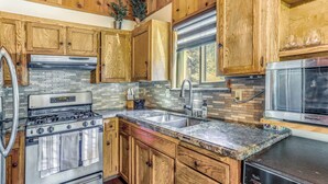 Una cocina con armarios de madera, una estufa de acero inoxidable, un fregadero y un microondas.