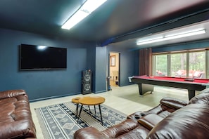 Ein Zimmer mit Pooltisch, Ledersesseln, Fernseher und Soundsystem.