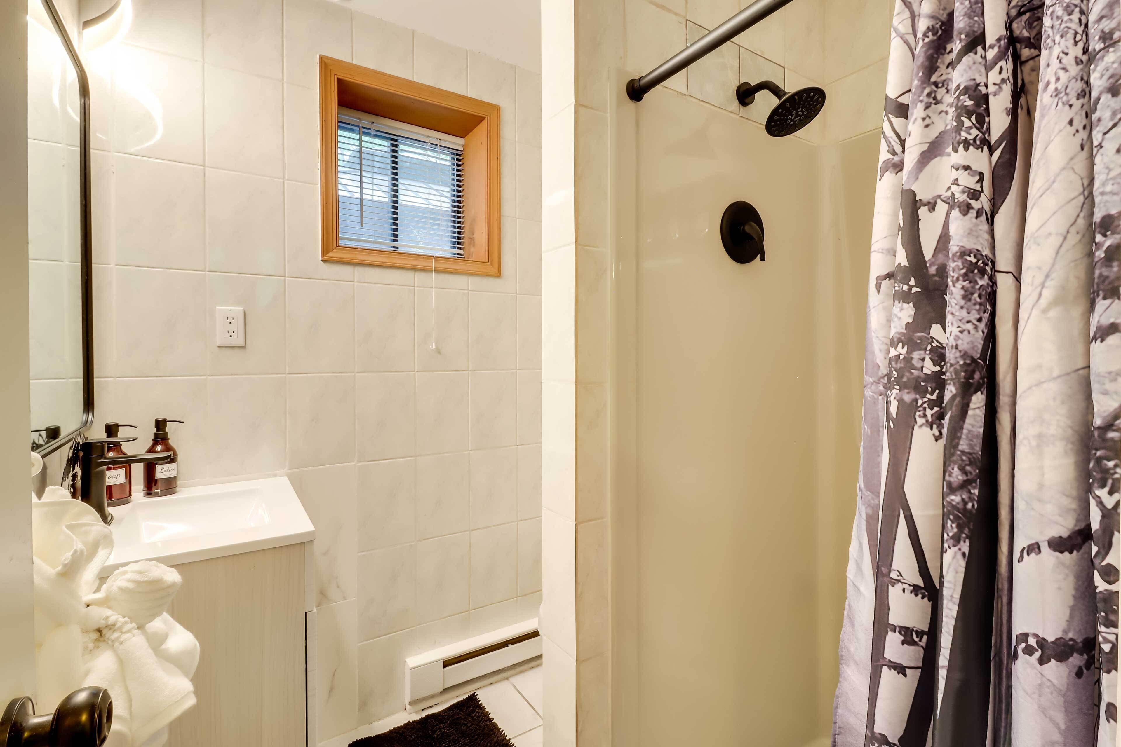 Un baño con ducha, ventana y lavamanos.