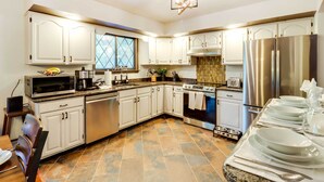 Una cocina moderna con armarios blancos, electrodomésticos de acero inoxidable y piso de baldosas.