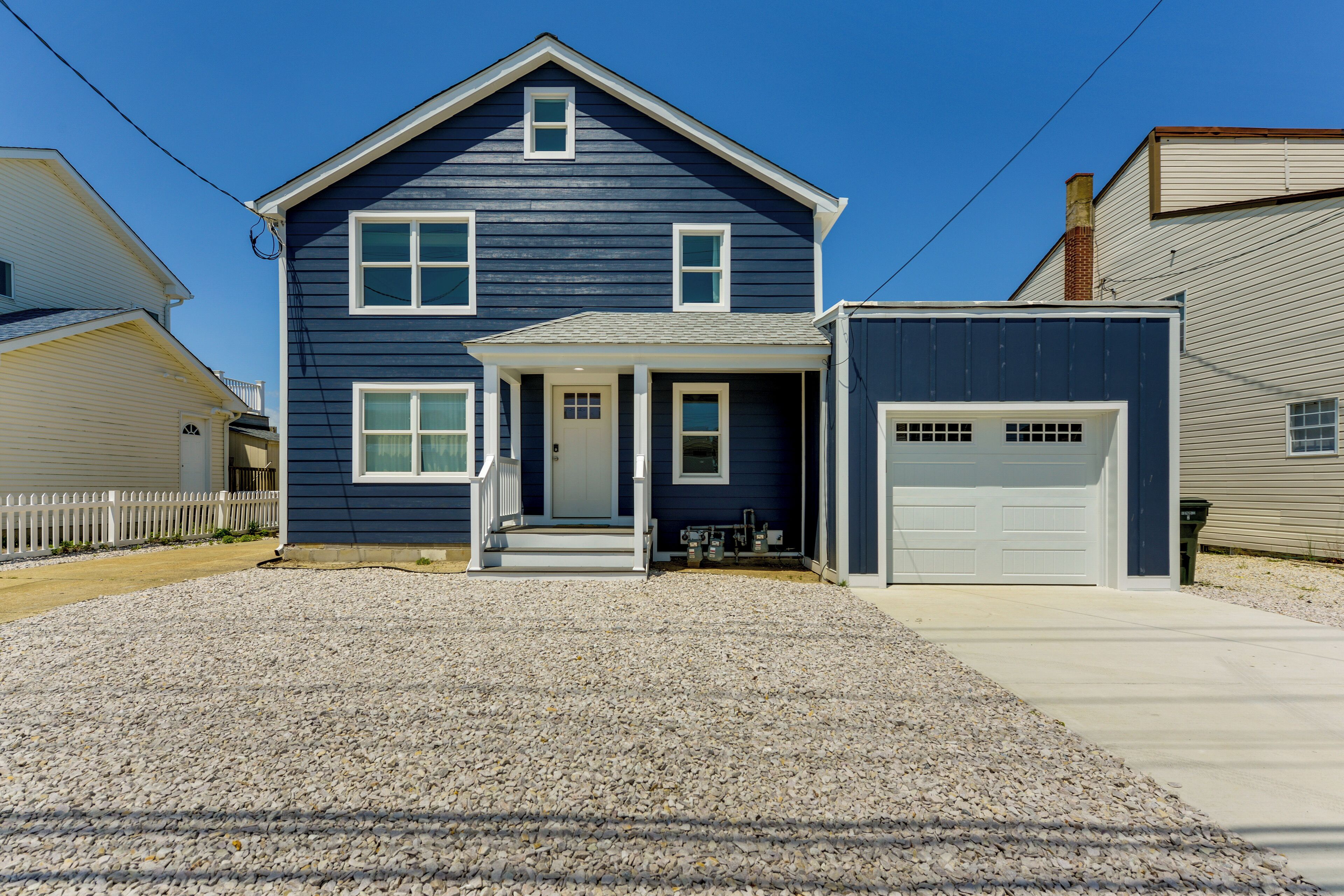 Une maison à deux étages avec un porche à l’avant, un garage et une allée gravillonnée.