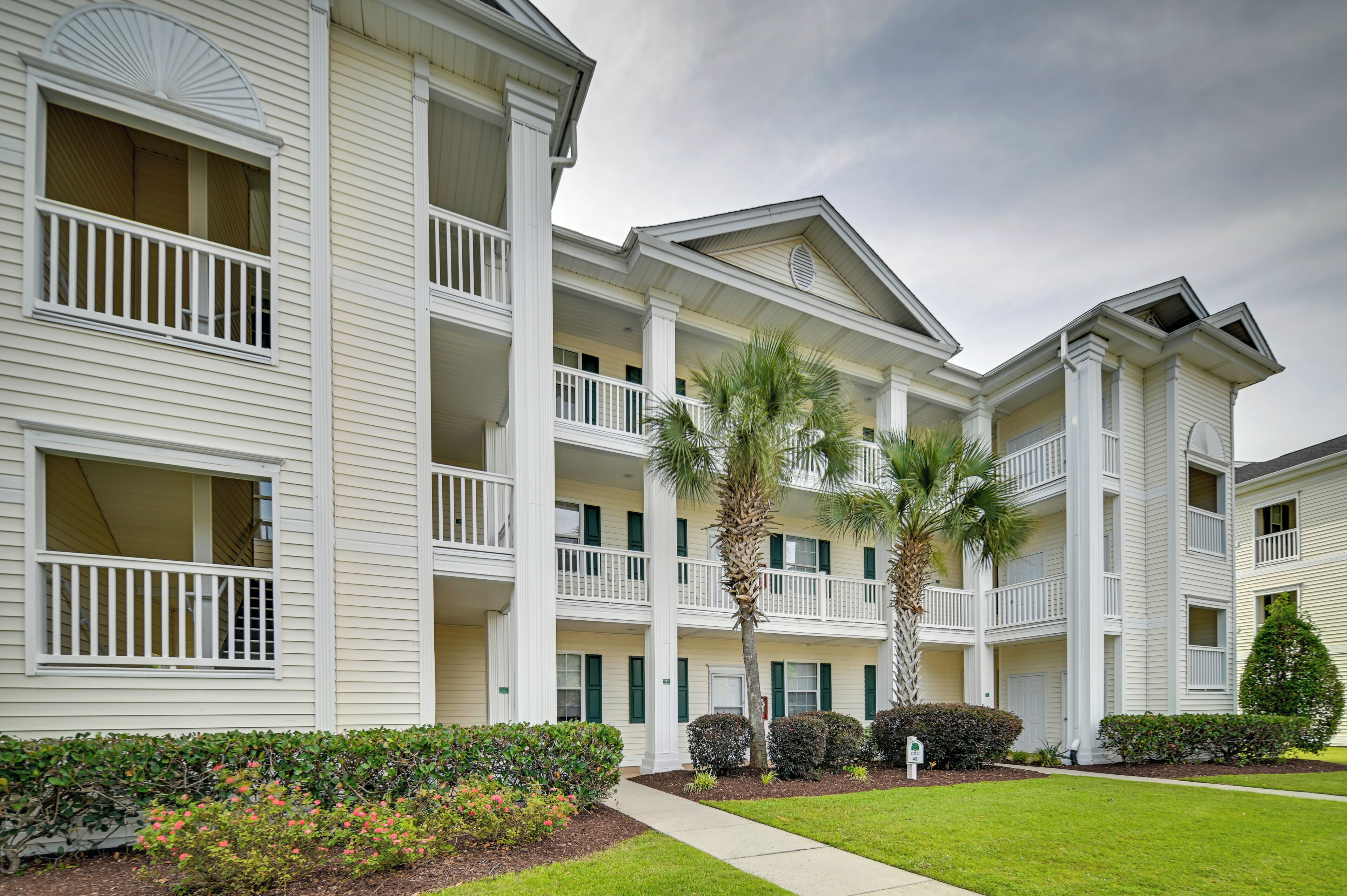 A multi-story hotel with balconies, palm trees, and well-maintained landscaping.