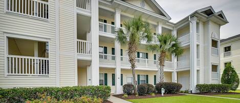 A multi-story hotel with balconies, palm trees, and well-maintained landscaping.