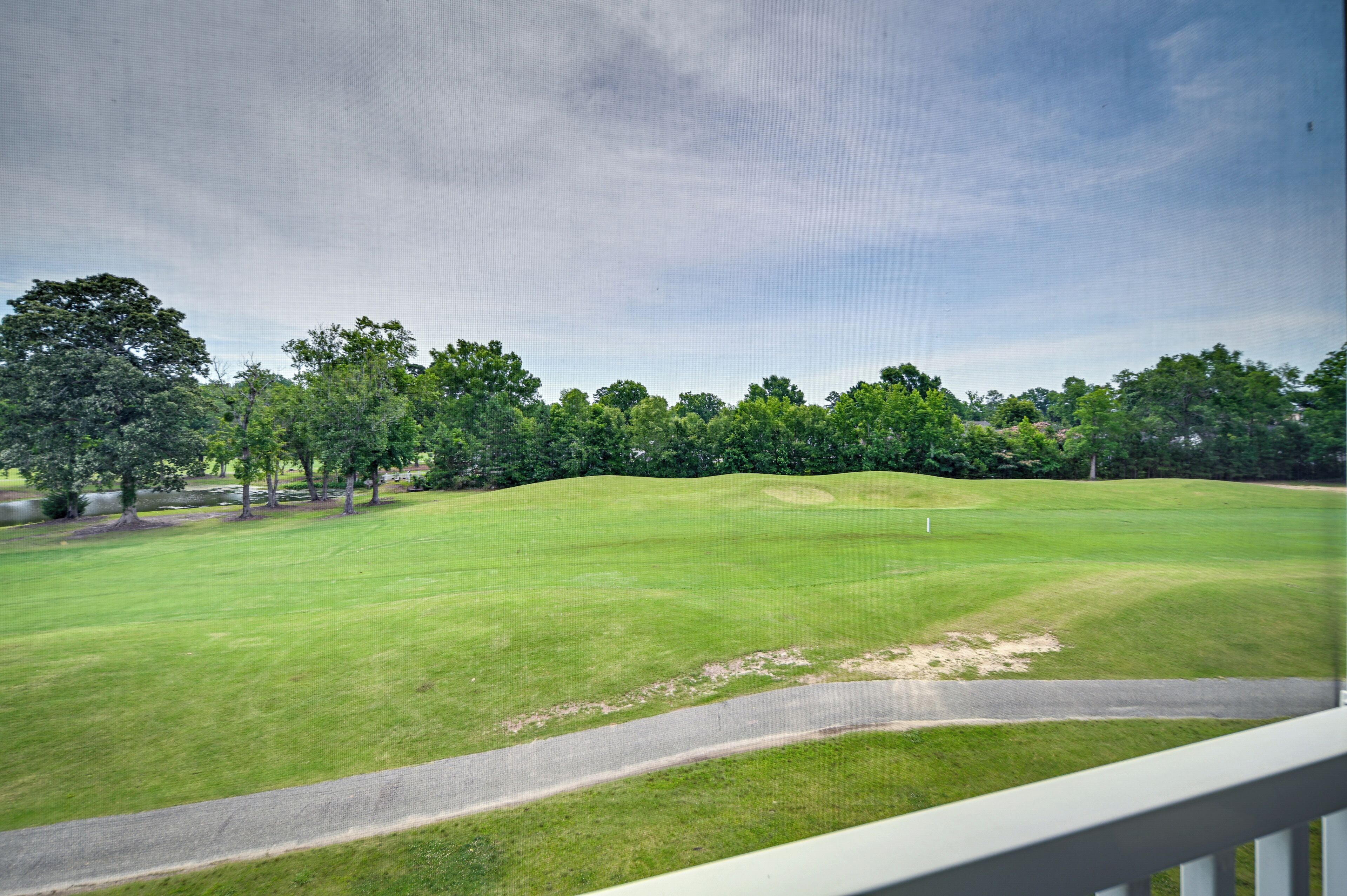 Un campo da golf con un green curato, una buca di sabbia e un cielo sereno.