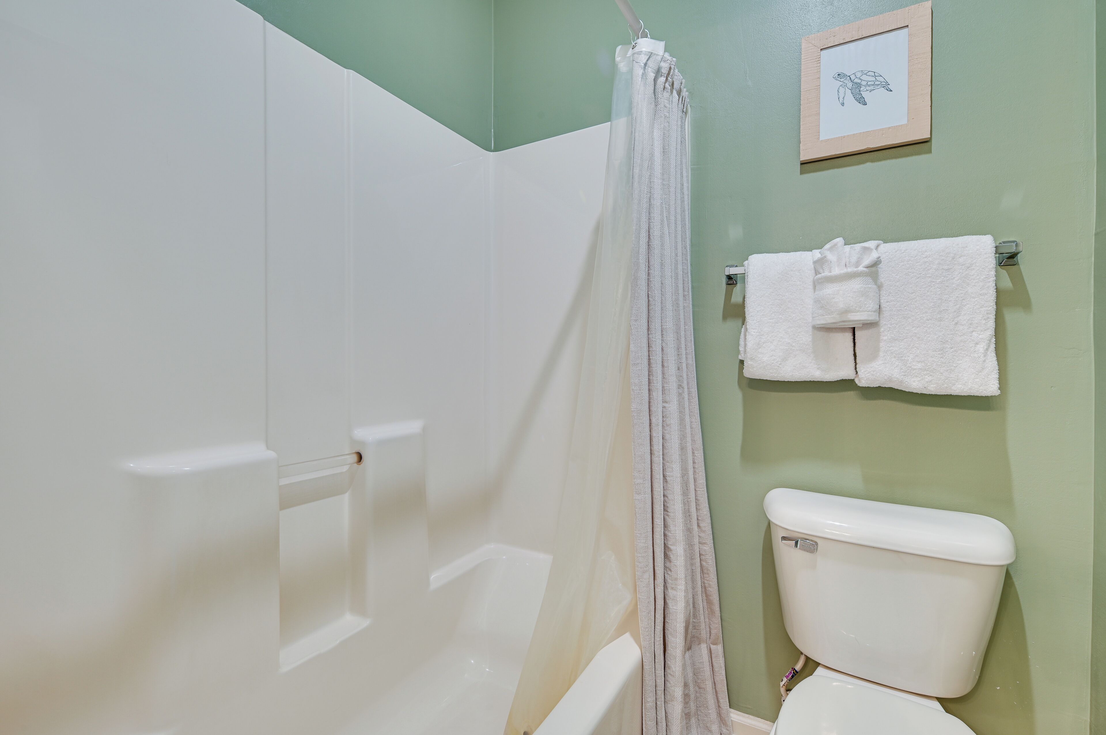 A bathroom with a shower curtain, a toilet, and a towel rack with towels.
