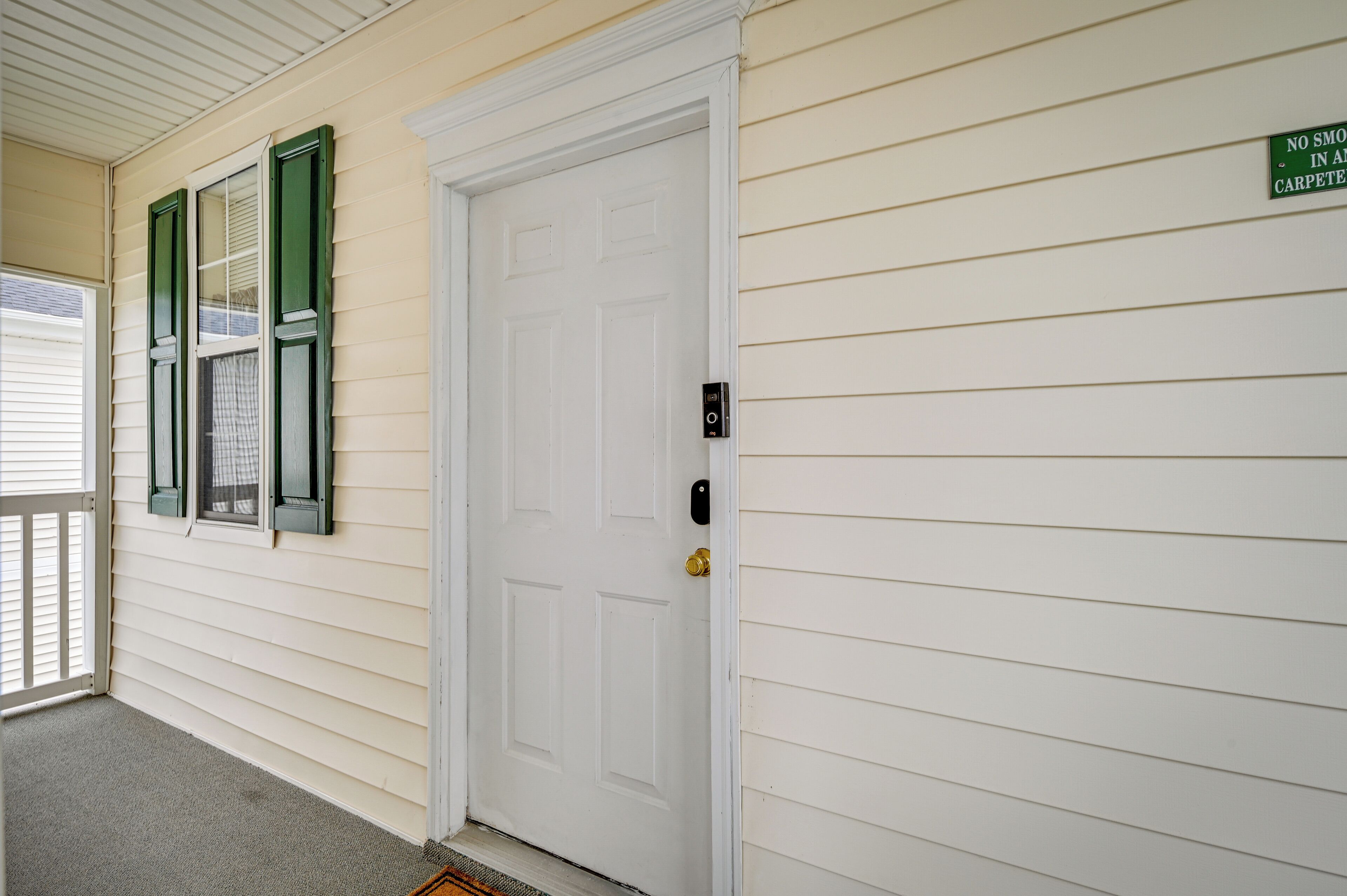 A white door with a green sign above it stating "NO SMOKE IN ANY CARPETED ROOM."