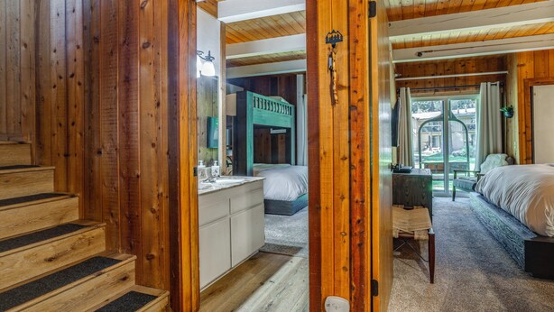A wooden interior with a staircase, a bed, a desk, and a view through a door. - Mammoth Lakes Vacation Rental: 1 Mi to Ski Area! (Mammoth Lakes)