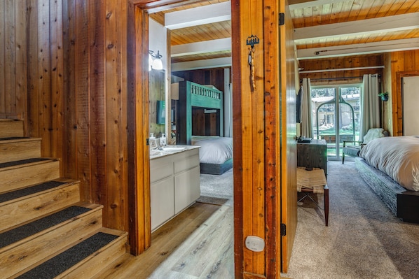 A wooden interior with a staircase, a bed, a desk, and a view through a door. - Mammoth Lakes Vacation Rental: 1 Mi to Ski Area! (Mammoth Lakes)