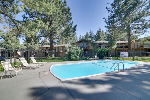 A swimming pool with lounge chairs and a fenced area, surrounded by trees and buildings. - Mammoth Lakes Vacation Rental: 1 Mi to Ski Area! (Mammoth Lakes)