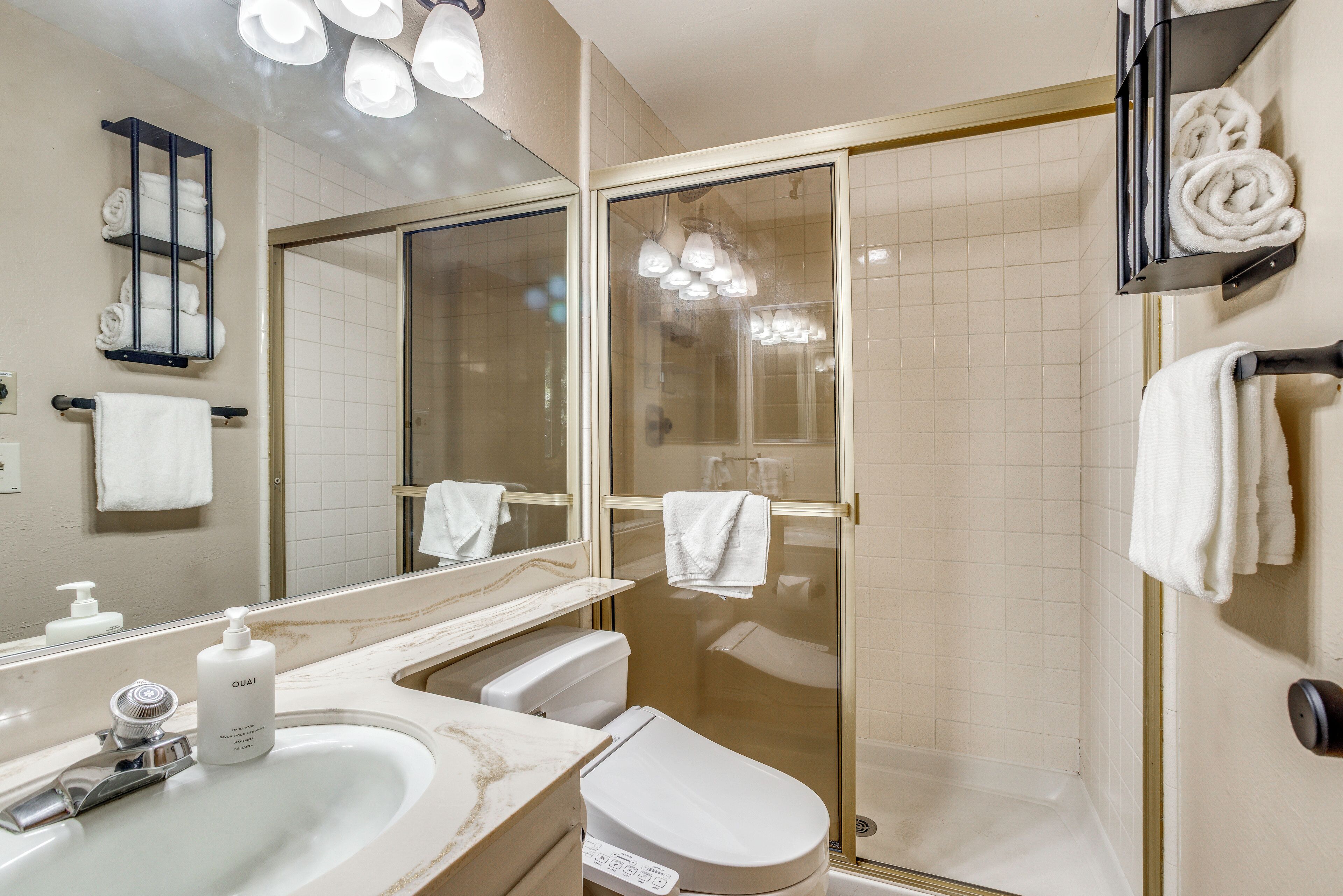 A bathroom with a sink, toilet, and glass shower enclosure.