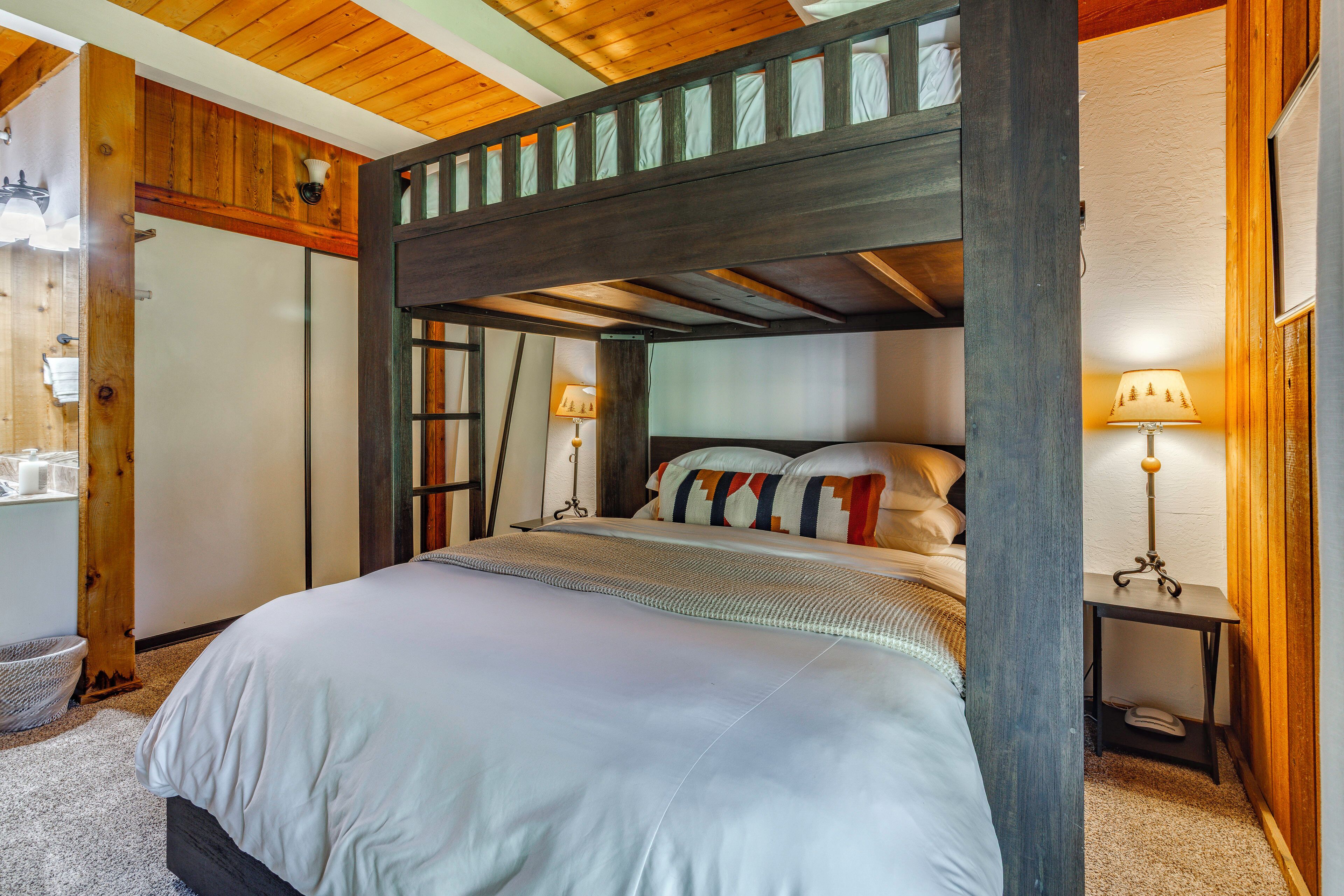 Een hemelbed met houten hoofdeinde, een nachtkastje met een lamp en een bijzettafeltje met lamp.