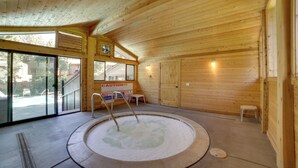 A wooden interior with a hot tub, glass doors leading outside, and a caution sign. - Mammoth Lakes Vacation Rental: 1 Mi to Ski Area! (Mammoth Lakes)