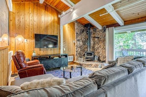 A cozy living room with a stone fireplace, a leather chair, a sofa, and a flat-screen TV. - Mammoth Lakes Vacation Rental: 1 Mi to Ski Area! (Mammoth Lakes)
