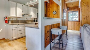A kitchen with white cabinets, a wooden island, and a bar area with stools. - Mammoth Lakes Vacation Rental: 1 Mi to Ski Area! (Mammoth Lakes)