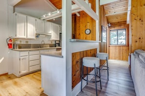 Una cocina con armarios blancos, una isla de madera y una zona de bar con taburetes.