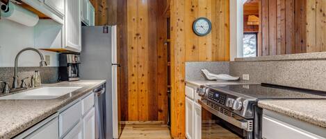 Une cuisine avec des murs en bois, un réfrigérateur en acier inoxydable, un four encastré et un plan de travail en granit.
