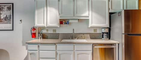A kitchen with white cabinets, a stainless steel refrigerator, a built-in oven, and a coffee maker.
