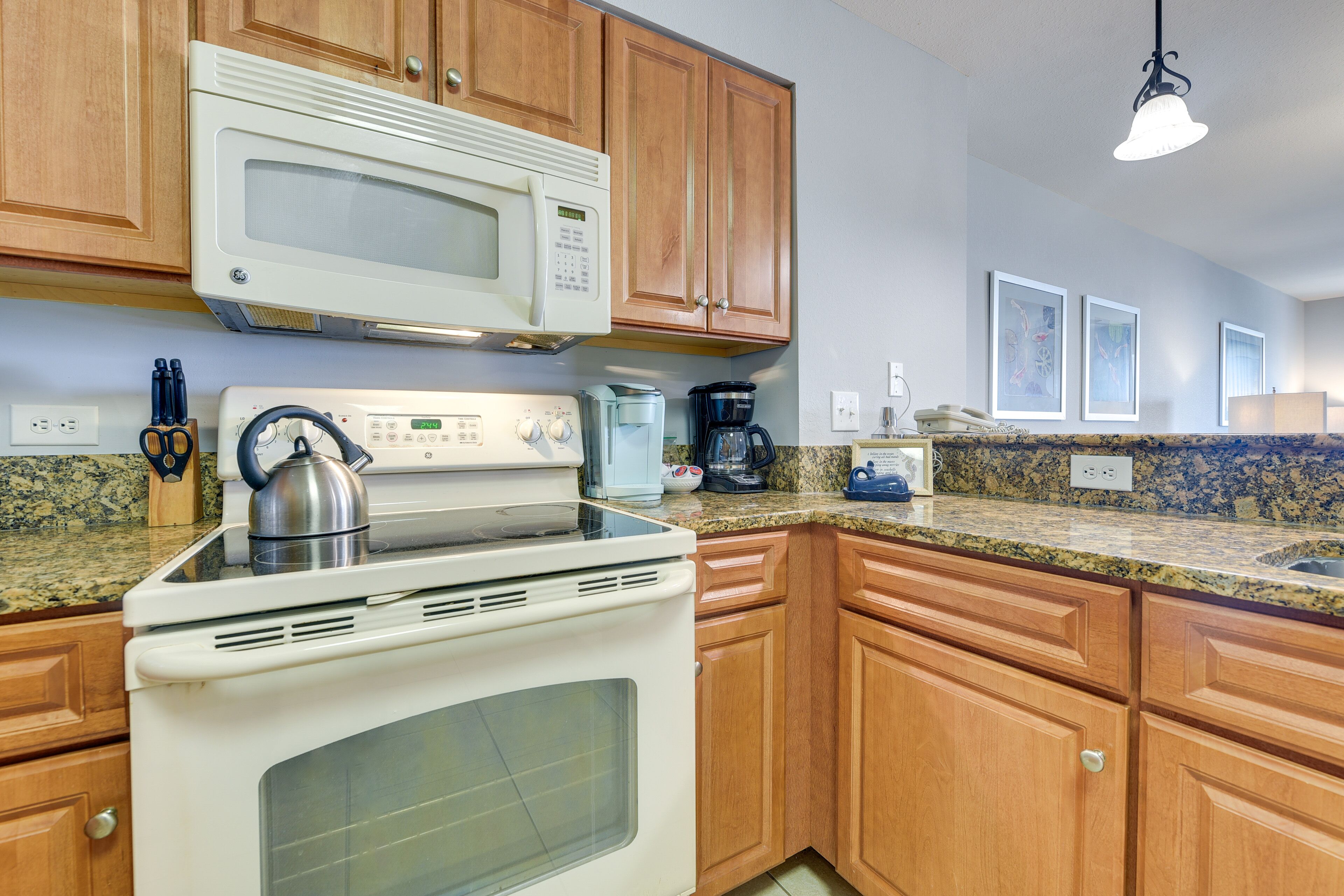 A kitchen with wooden cabinets, a white stove, a microwave, and a coffee maker.