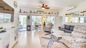 A spacious living room with a starfish-patterned rug, a ceiling fan, and nautical-themed decor. - Hot Tub & Gas Grill: Port Richey Retreat (Port Richey)