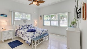 A bedroom with a bed, bedside tables, a ceiling fan, a window, and a wall-mounted TV. - Hot Tub & Gas Grill: Port Richey Retreat (Port Richey)
