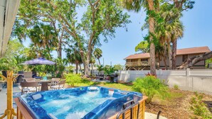 A hot tub in a backyard with a wooden deck, surrounded by palm trees and a fenced area. - Hot Tub & Gas Grill: Port Richey Retreat (Port Richey)