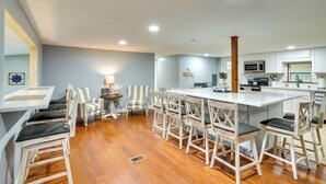 Une cuisine moderne avec des meubles blancs, un îlot central et un coin repas doté de chaises à rayures.