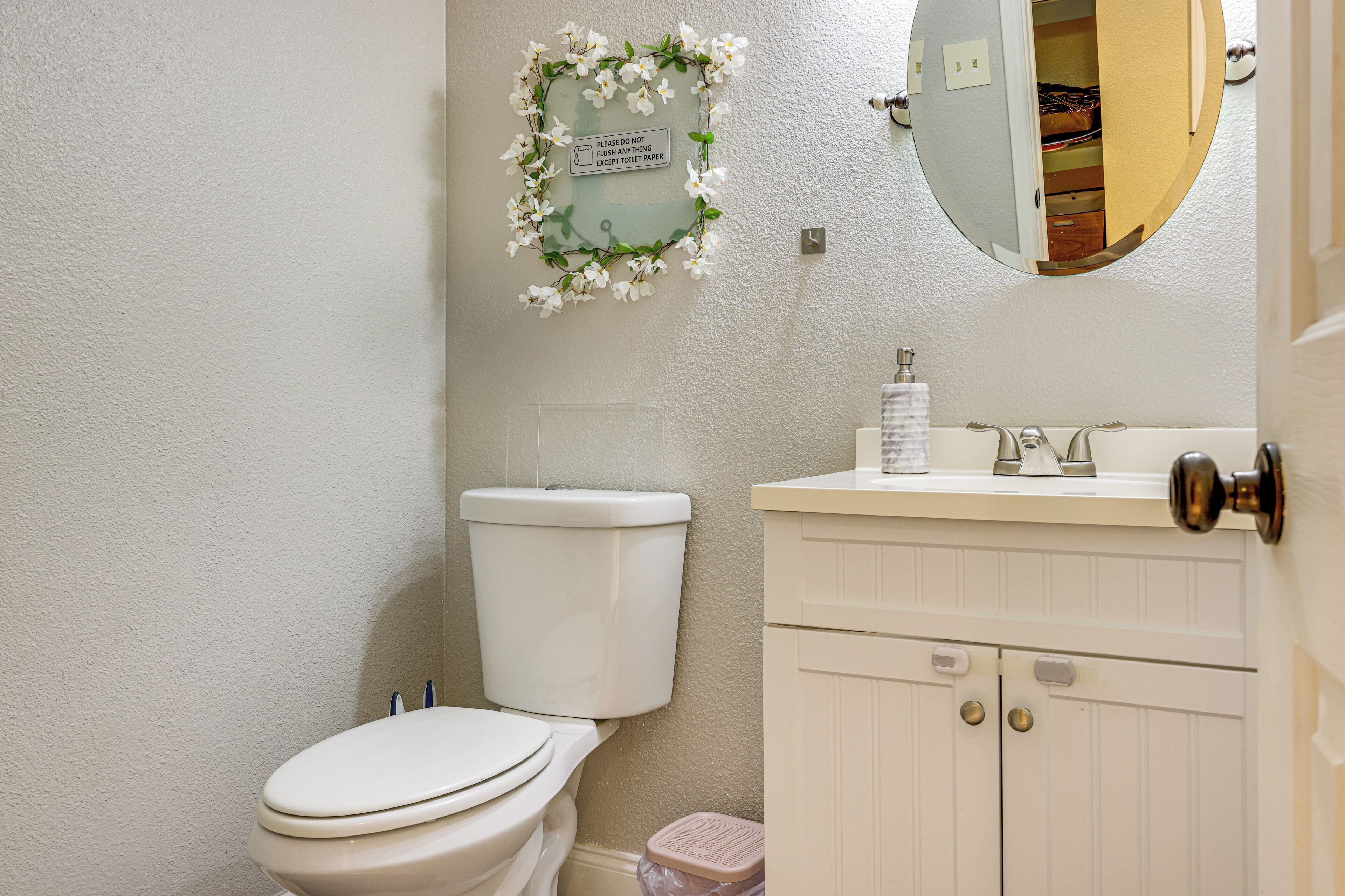A bathroom with a toilet, sink, and mirror.