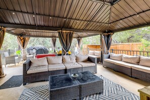 An outdoor covered patio with wicker furniture, a grill, and a dining area. - Covered Patio + Game Room: New Braunfels Home! (New Braunfels)