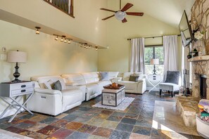 A spacious living room with a sectional sofa, a fireplace, and a stone-tiled floor. - Covered Patio + Game Room: New Braunfels Home! (New Braunfels)