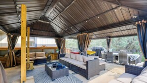 Un espace extérieur aménagé en terrasse, avec des meubles en osier, une table en bois et un plafond couvert.