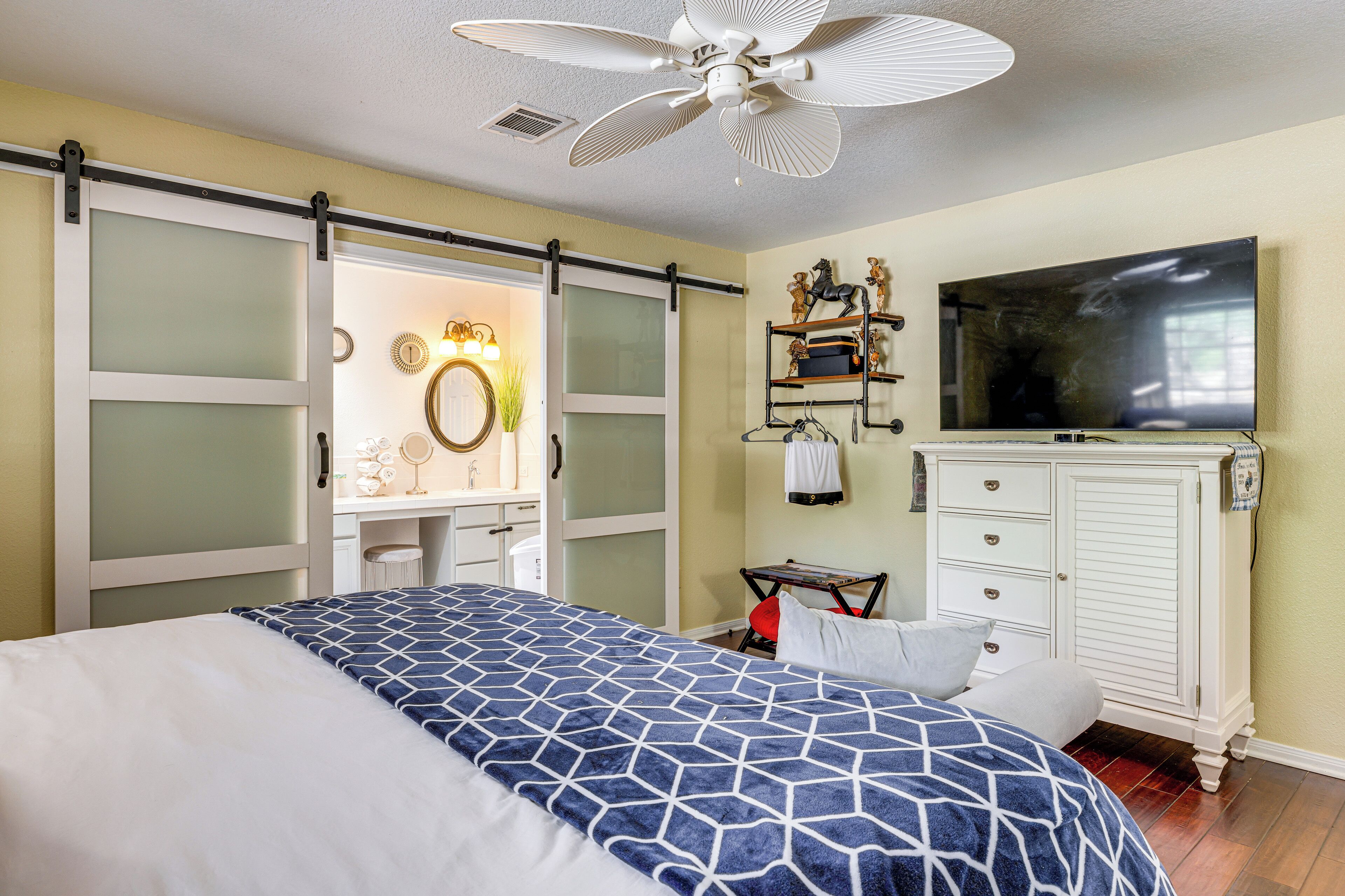 A bedroom with a bed, a TV, a wardrobe, and a desk with a chair.