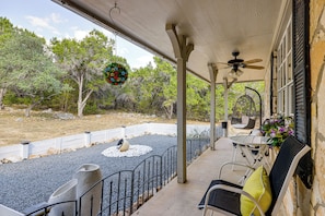 A covered outdoor patio with a ceiling fan, a white table with chairs, and a decorative wreath. - Covered Patio + Game Room: New Braunfels Home! (New Braunfels)