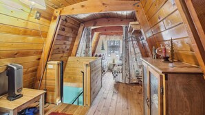 A cozy attic bedroom with wooden walls, a desk with a computer, a bed, and a small table with a candle. - Near Trails: Forest Lake Retreat w/ Backyard Oasis (Forest Lakes)