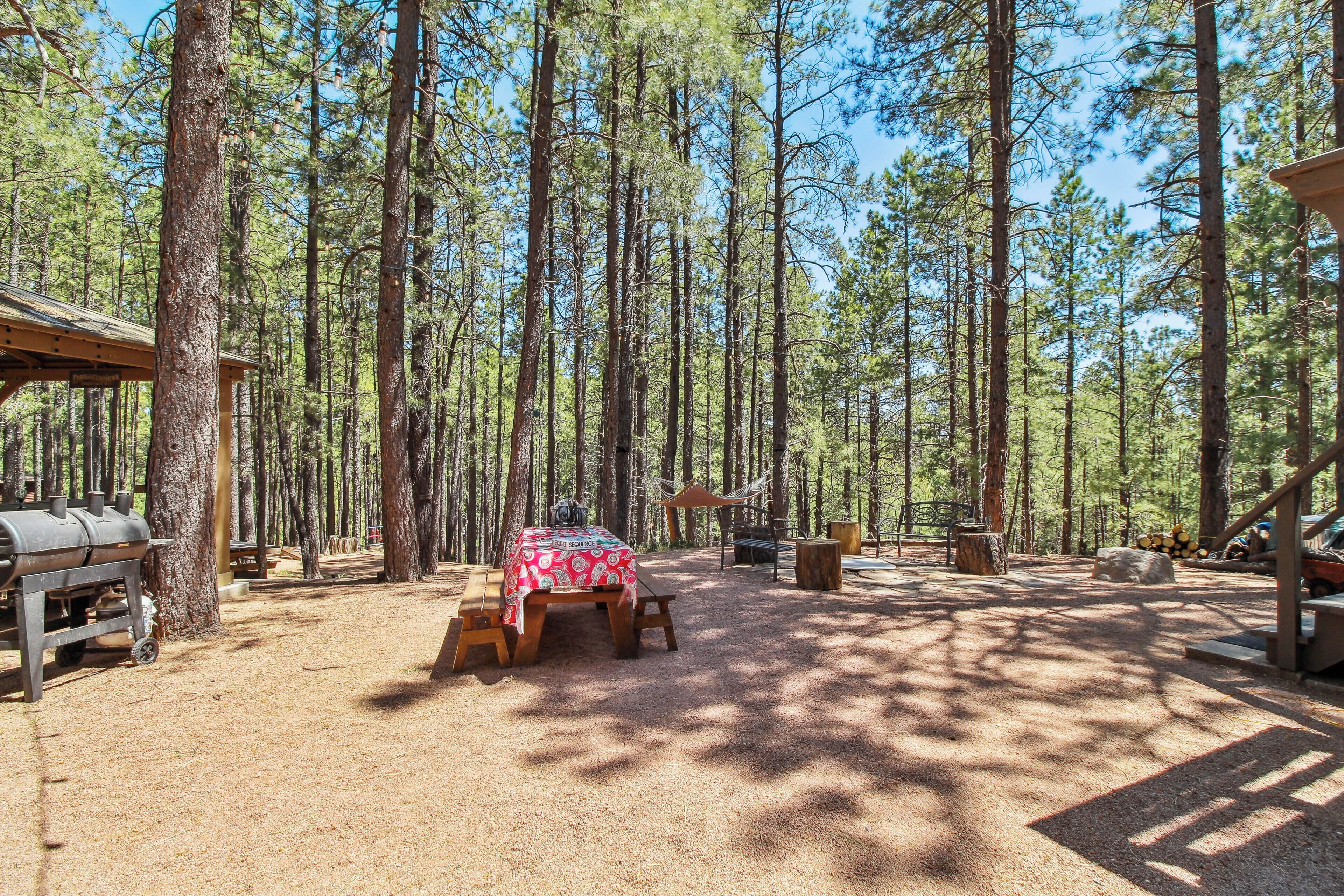 A campsite with a picnic table, barbecue grill, and wooden structures.