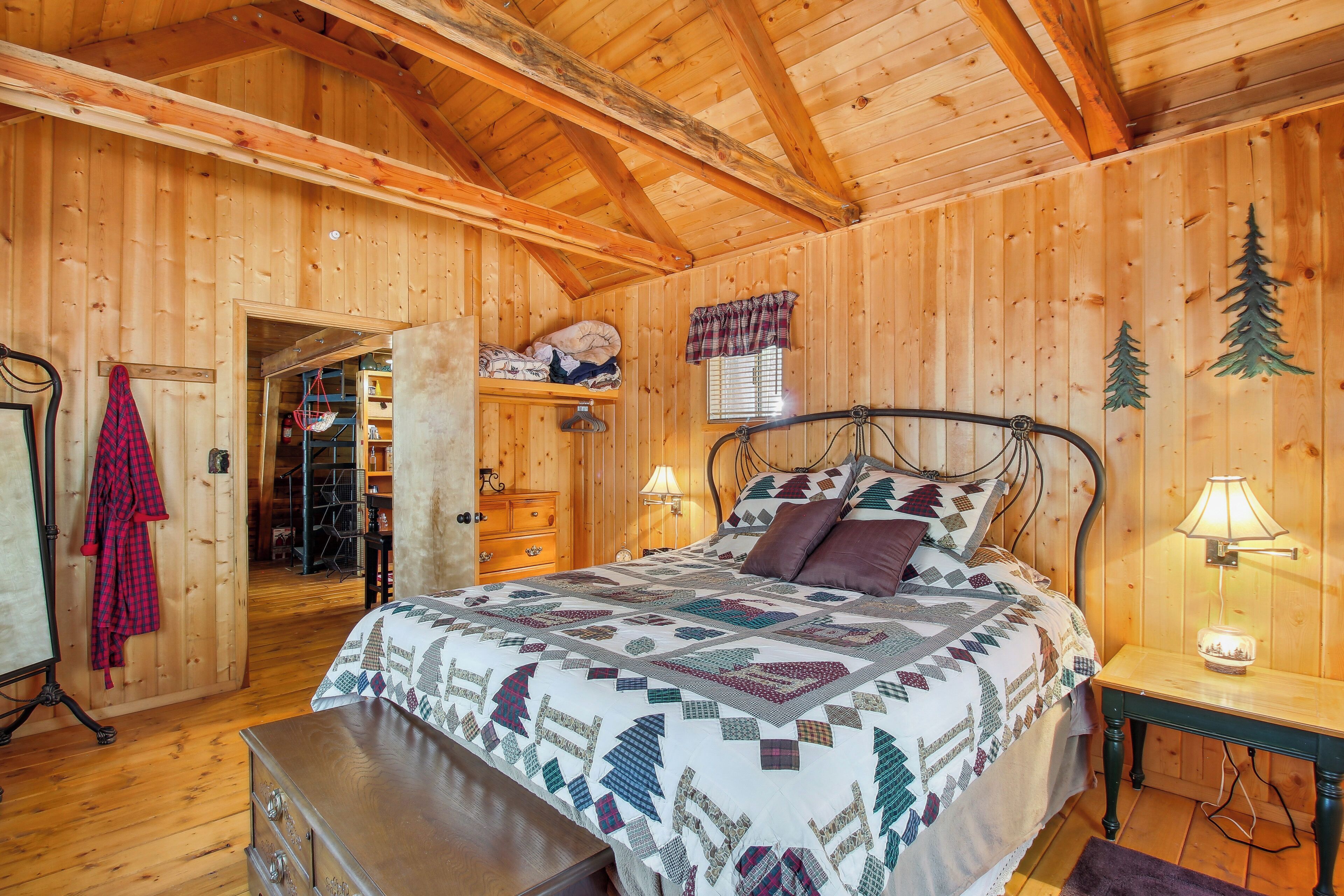 A wooden cabin bedroom with a bed, nightstands, a dresser, and a walk-in closet.