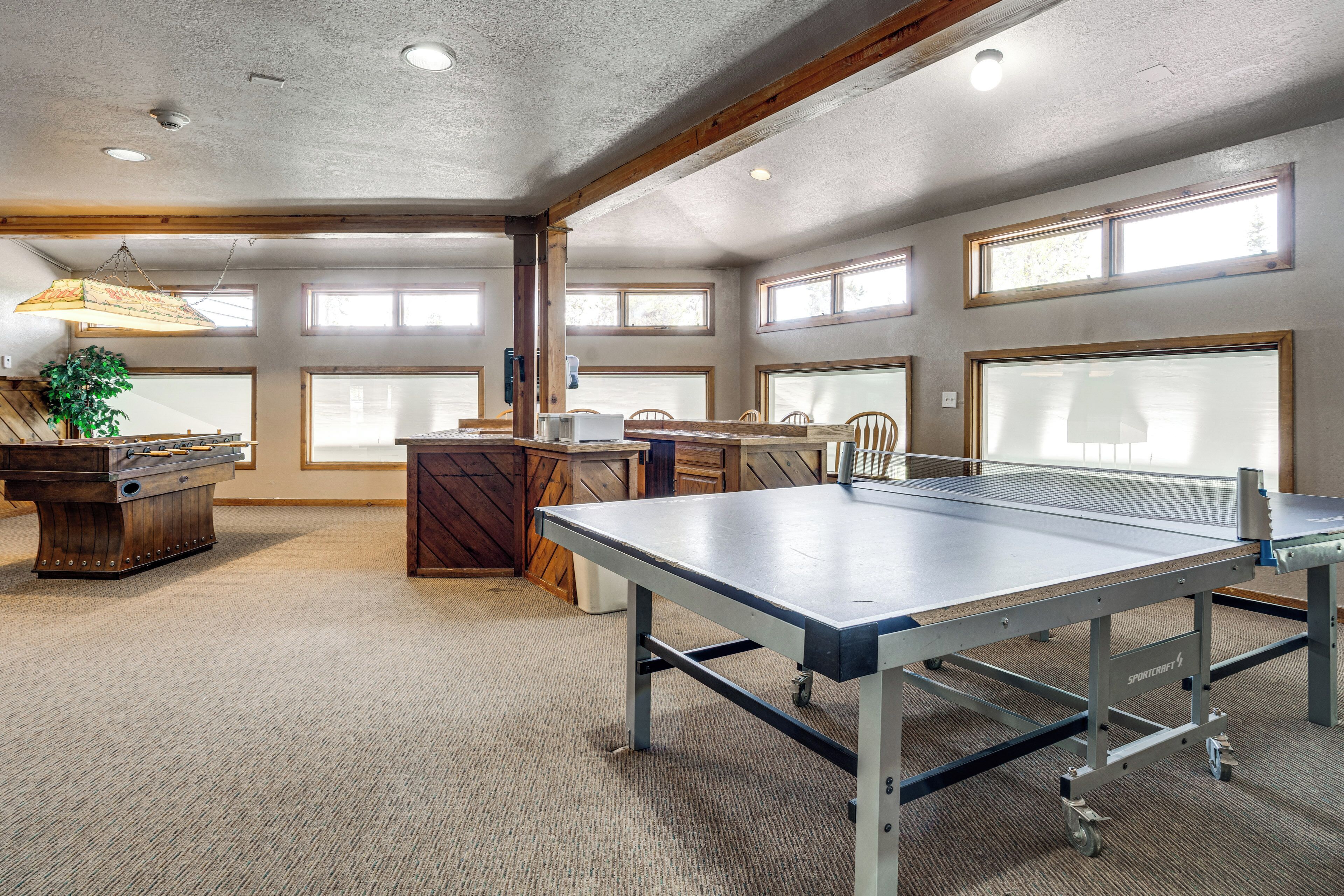 Una habitación amplia con mesa de ping pong, un mueble de madera y un ventanal grande.