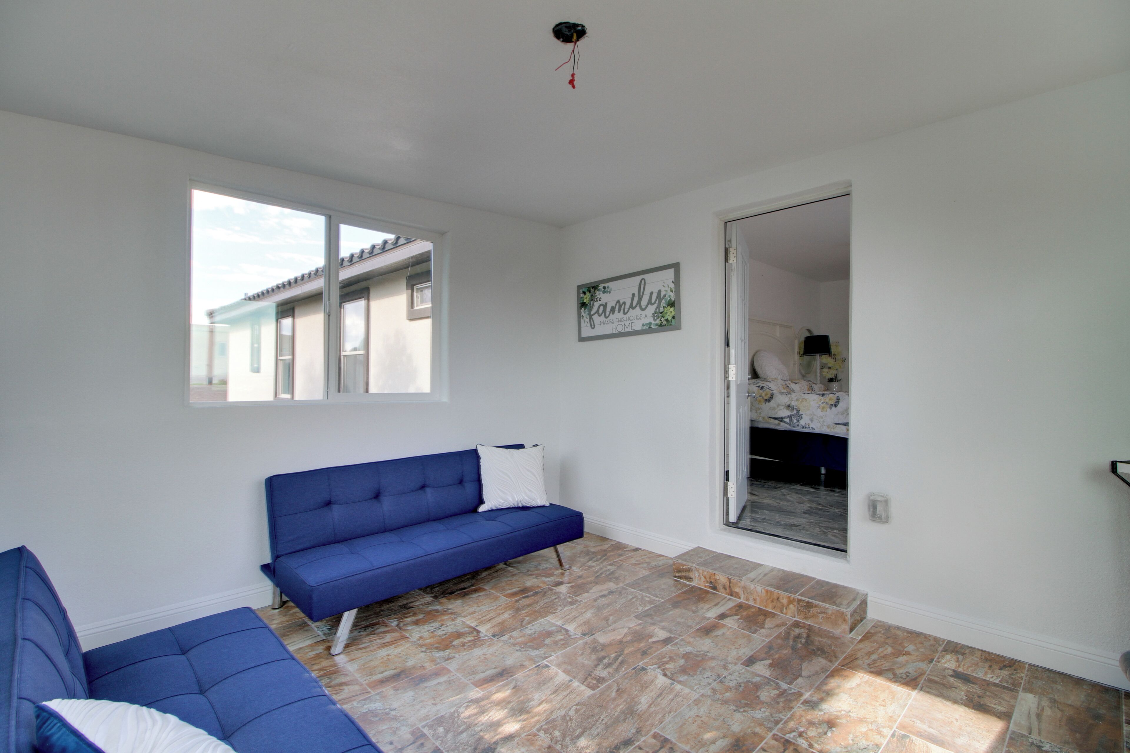 A room with a blue sofa, a large window, and a door leading to a balcony.
