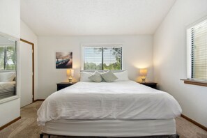 A bedroom with a large bed, two bedside tables with lamps, a window with blinds, and a picture on the wall. - Lake Ozark Vacation Rental w/ Pool Access (Lake Ozark)