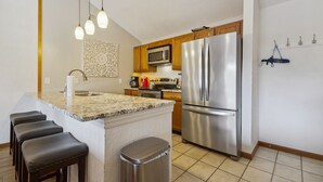 A kitchen with a central island, stainless steel appliances, wooden cabinets, and pendant lighting. - Lake Ozark Vacation Rental w/ Pool Access (Lake Ozark)